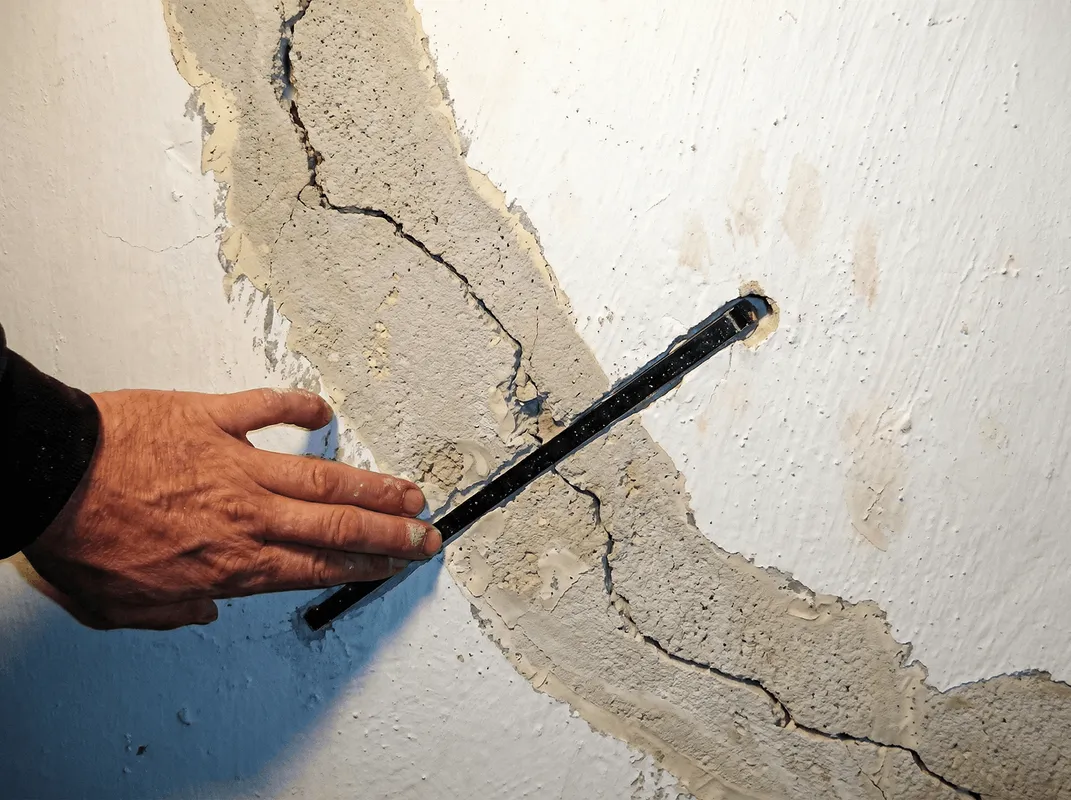 A wall with a large crack is being inspected by a professional in Tallahassee, FL